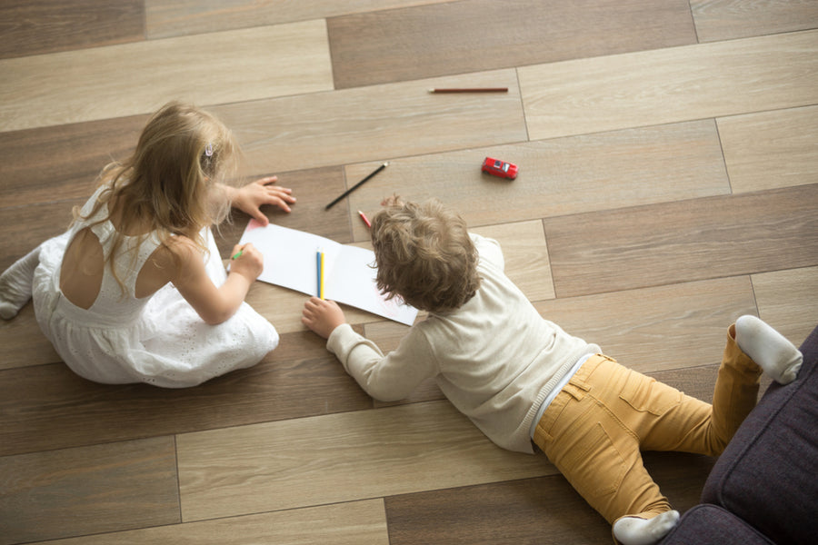 Kids sister and brother playing drawing together on wooden warm floor in living room